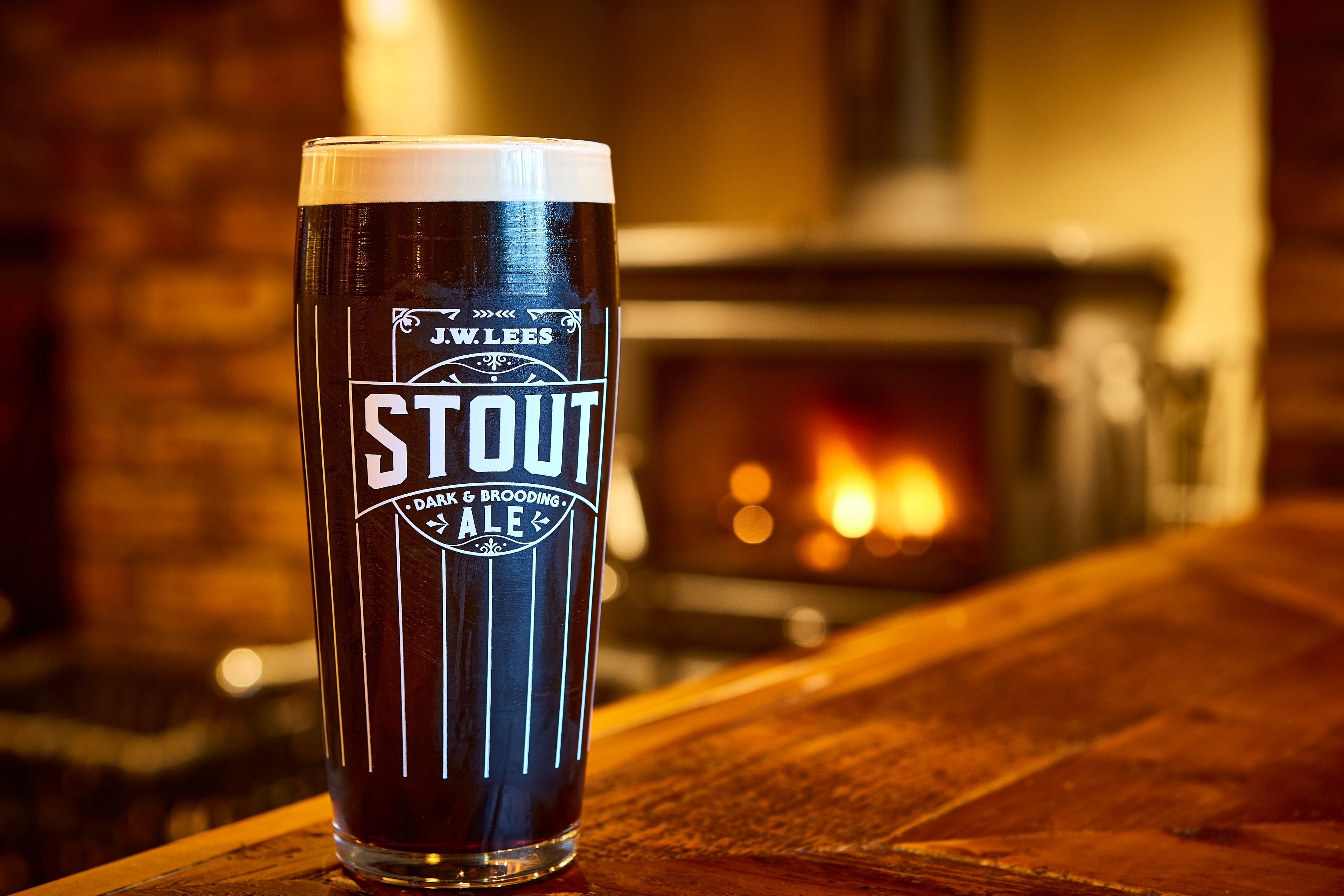 JW Lees stout glass in front of fire