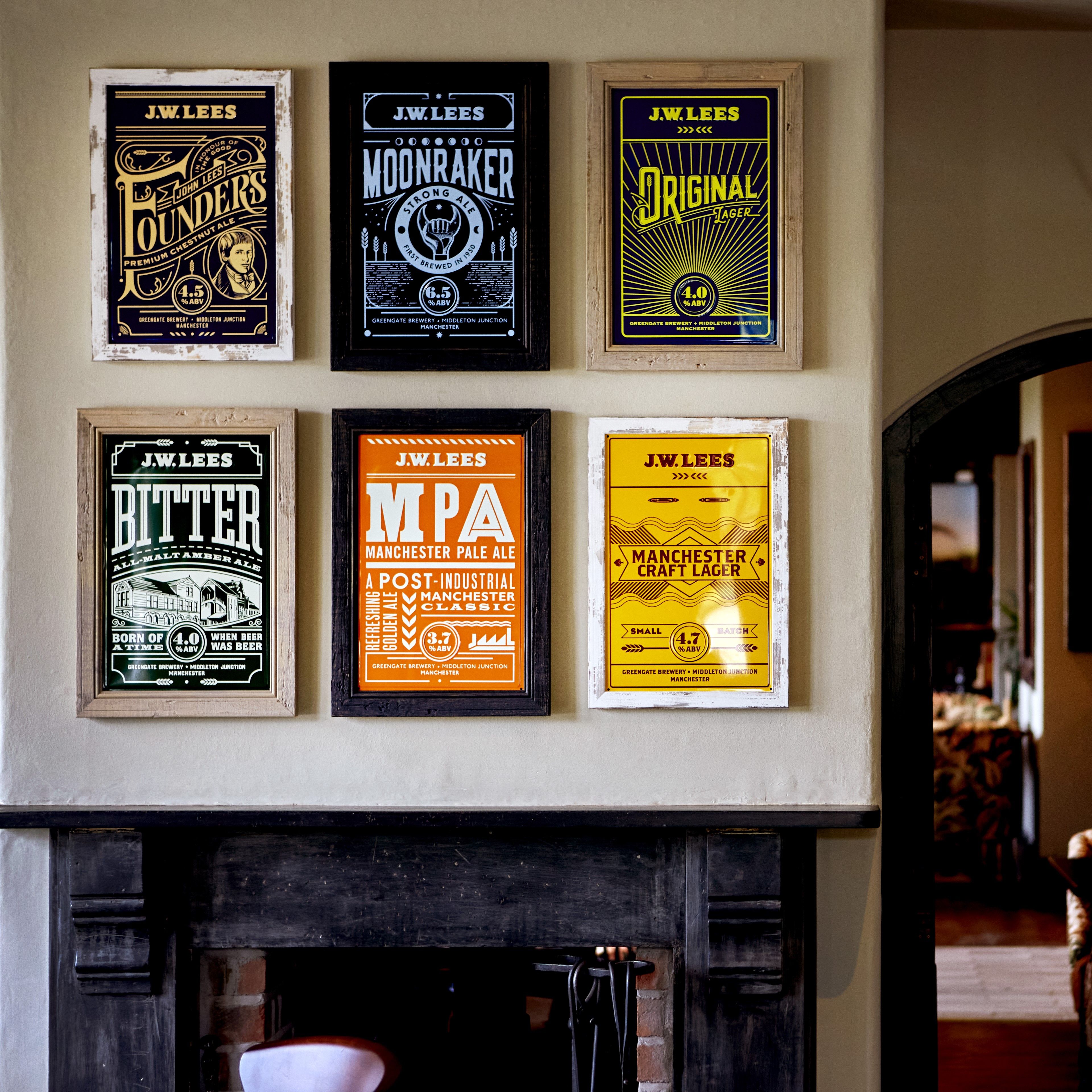 Posters of the core beers above a fire in a JW Lees pub